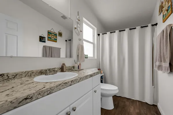 a bathroom with a granite countertop sink toilet and a mirror