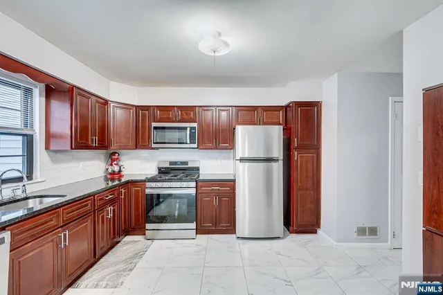 a kitchen with stainless steel appliances granite countertop a refrigerator stove top oven and sink