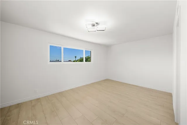 an empty room with a chandelier fan and windows