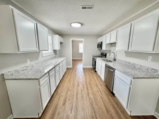 a kitchen with cabinets stainless steel appliances and wooden floor