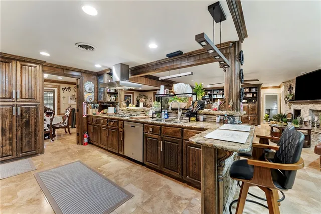 a room with lots of wooden furniture a sink a window and stainless steel appliances