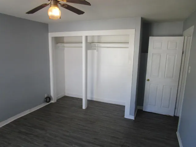 an empty room with wooden floor fan and window