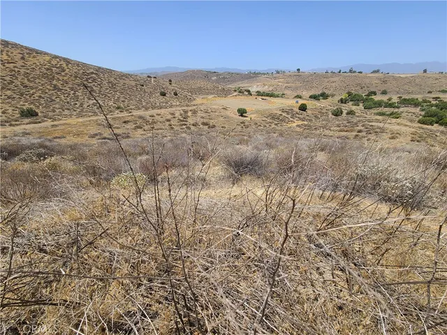 a view of a dry yard with wooden fence