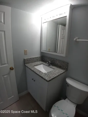a bathroom with a granite countertop sink toilet and mirror