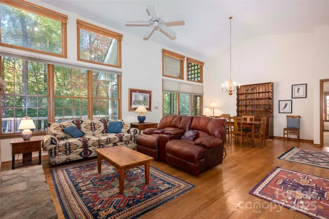 a living room with furniture large windows and wooden floor