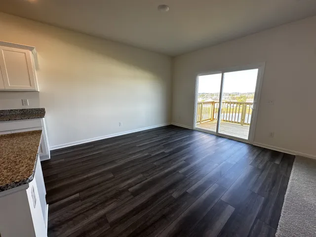 a living room with stainless steel appliances furniture a rug and a kitchen view