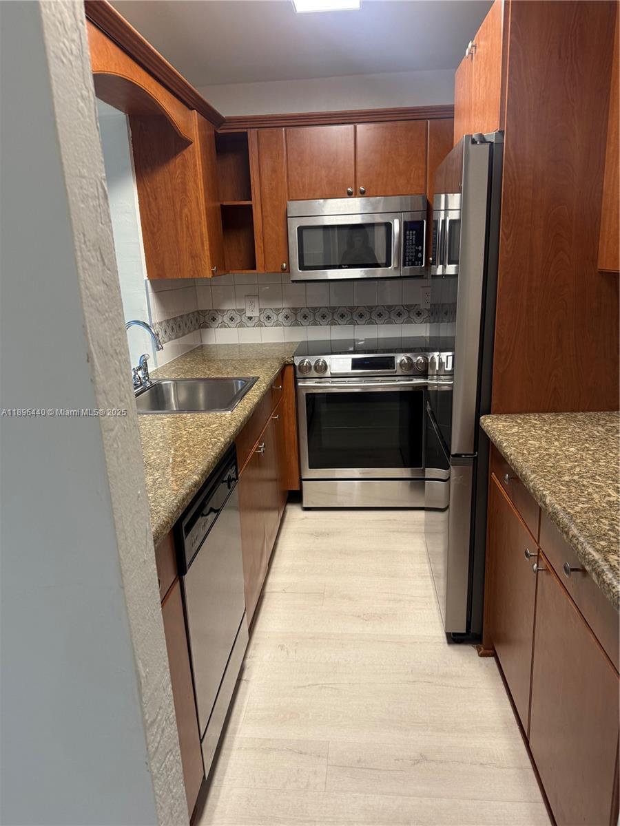 7403 Southwest 82nd Street, Unit 109N Miami, FL 33143 - Photo 5 of 16 a kitchen with granite countertop a stove and a microwave