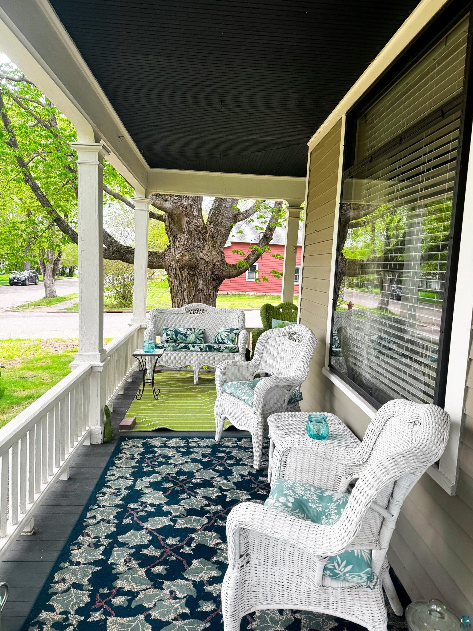 303 East 5th Street Washburn, WI 54891 - Photo 11 of 34 Inviting covered porch featuring a painted wood plank floor, white balustrade, and substantial square columns