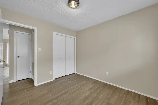 a view of an empty room with wooden floor and closet