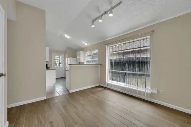 a view of an empty room with wooden floor and a window