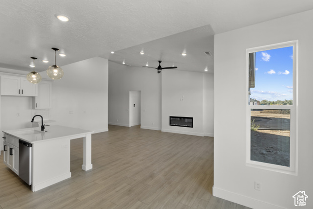 205 East 690th Street North Logan, UT 84321 - Photo 26 of 52 Open-concept interior featuring wood-finish flooring, recessed lighting, a built-in electric fireplace, and a kitchen island with a sink and pendant lighting