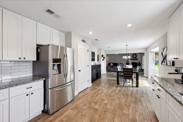 a kitchen with stainless steel appliances a refrigerator a stove a dining table and chairs with wooden floor