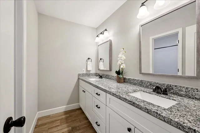 a bathroom with a granite countertop double vanity sink and a mirror