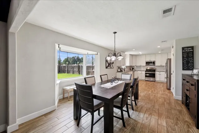 a view of a dining room and livingroom with furniture wooden floor a rug a chandelier