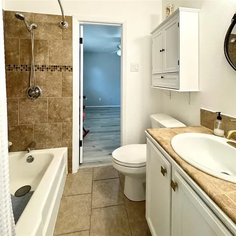 a bathroom with a granite countertop sink a toilet and shower