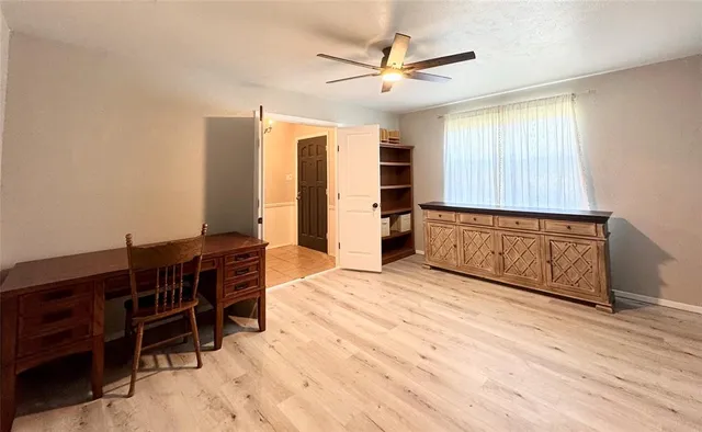 a view of empty room with wooden floor and fan