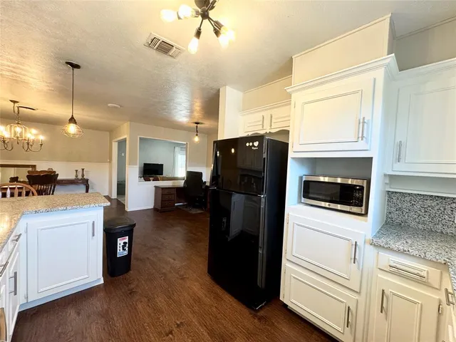 a kitchen with stainless steel appliances kitchen island granite countertop a refrigerator a stove a microwave oven a sink with island and chairs