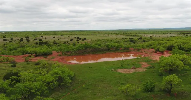 an aerial view of a houses with outdoor space and trees all around