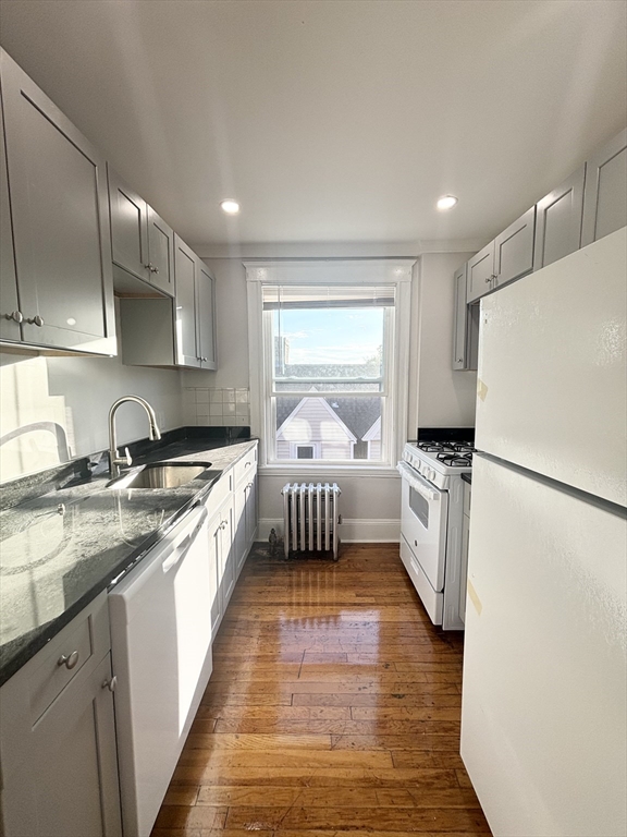 a large white kitchen with a sink stainless steel appliances and cabinets