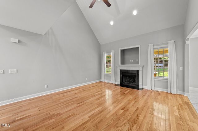 a view of empty room with wooden floor and fireplace