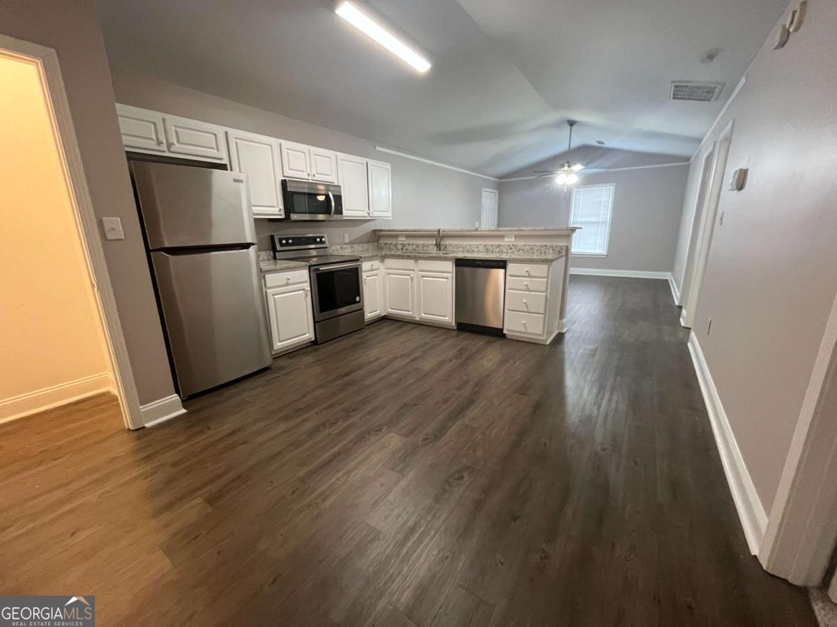 565 Rustwood Drive Athens, GA 30606 - Photo 2 of 16 a kitchen with wooden floors white cabinets and stainless steel appliances