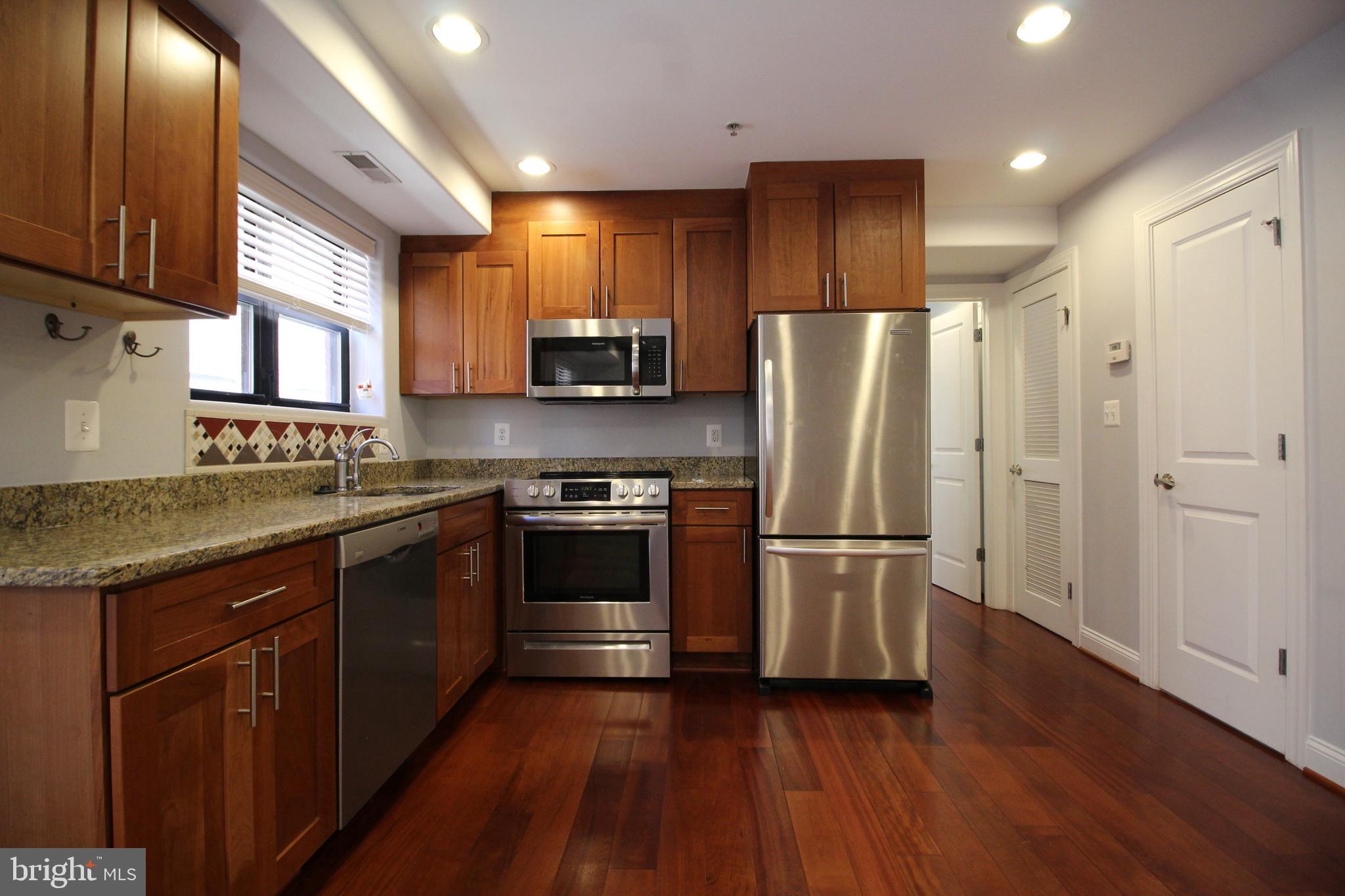 1354 Euclid Street Northwest, Unit 303B Washington, DC 20009 - Photo 9 of 16 a kitchen with stainless steel appliances granite countertop a refrigerator stove and sink