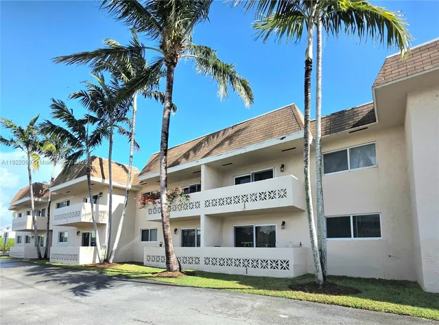a view of a white house with a small yard and palm trees