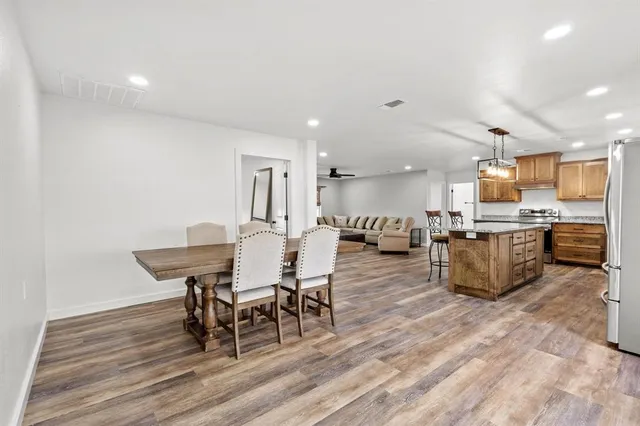 a dining room with kitchen island stainless steel appliances furniture a dining table and chairs