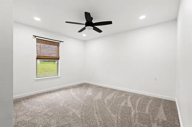 an empty room with a window and a ceiling fan