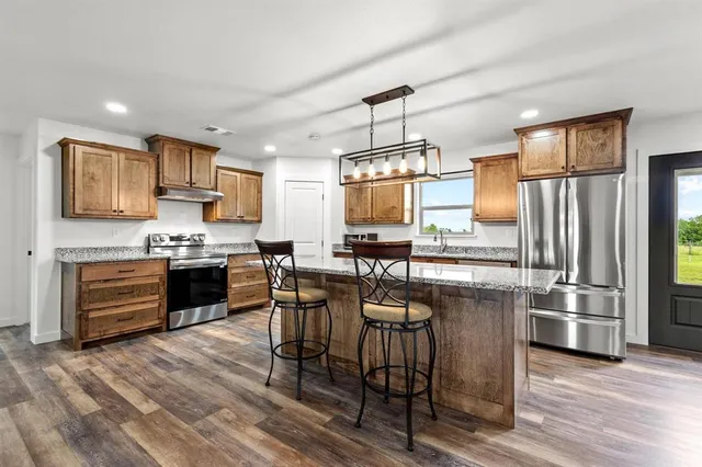 a kitchen with granite countertop a refrigerator stove microwave and sink