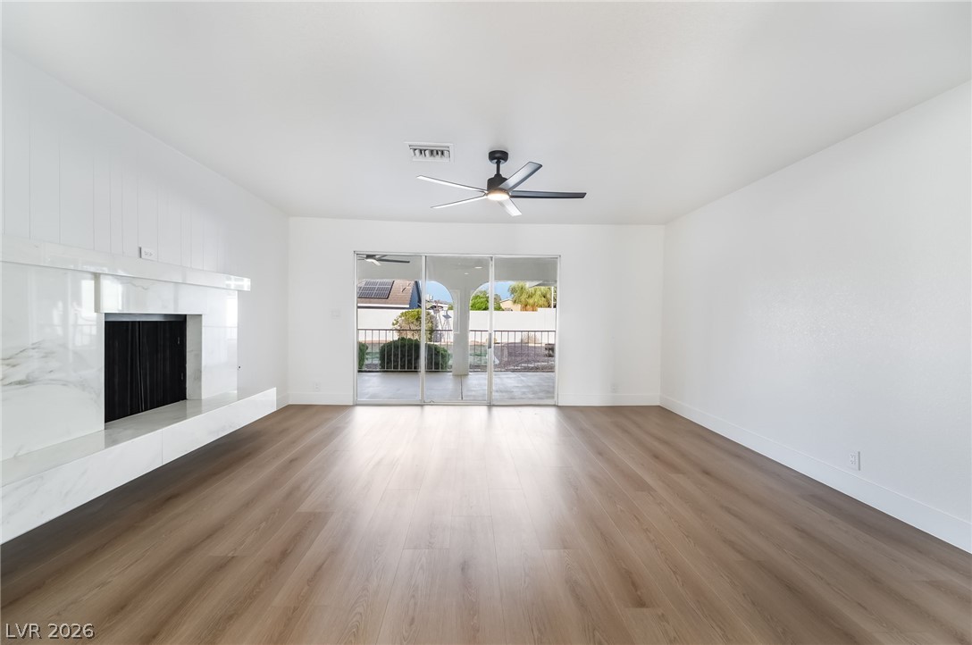 429 Crestway Road Henderson, NV 89015 - Photo 10 of 56 A spacious living room features elegant wood flooring, a fireplace, and glass sliding doors opening to a balcony.