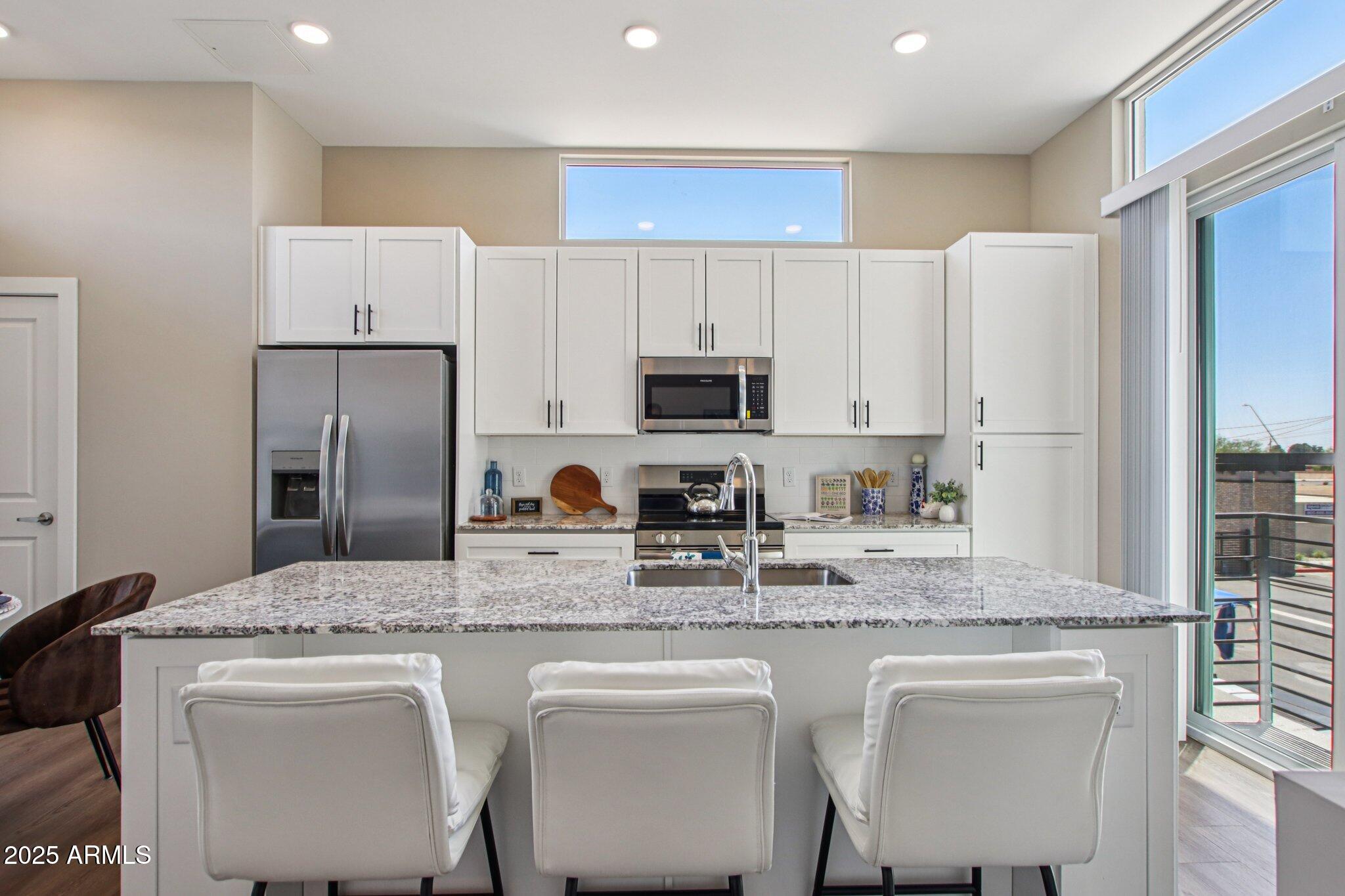 1927 South Recker Road, Unit 163 Mesa, AZ 85206 - Photo 10 of 34 a kitchen with stainless steel appliances granite countertop a dining table chairs refrigerator and sink