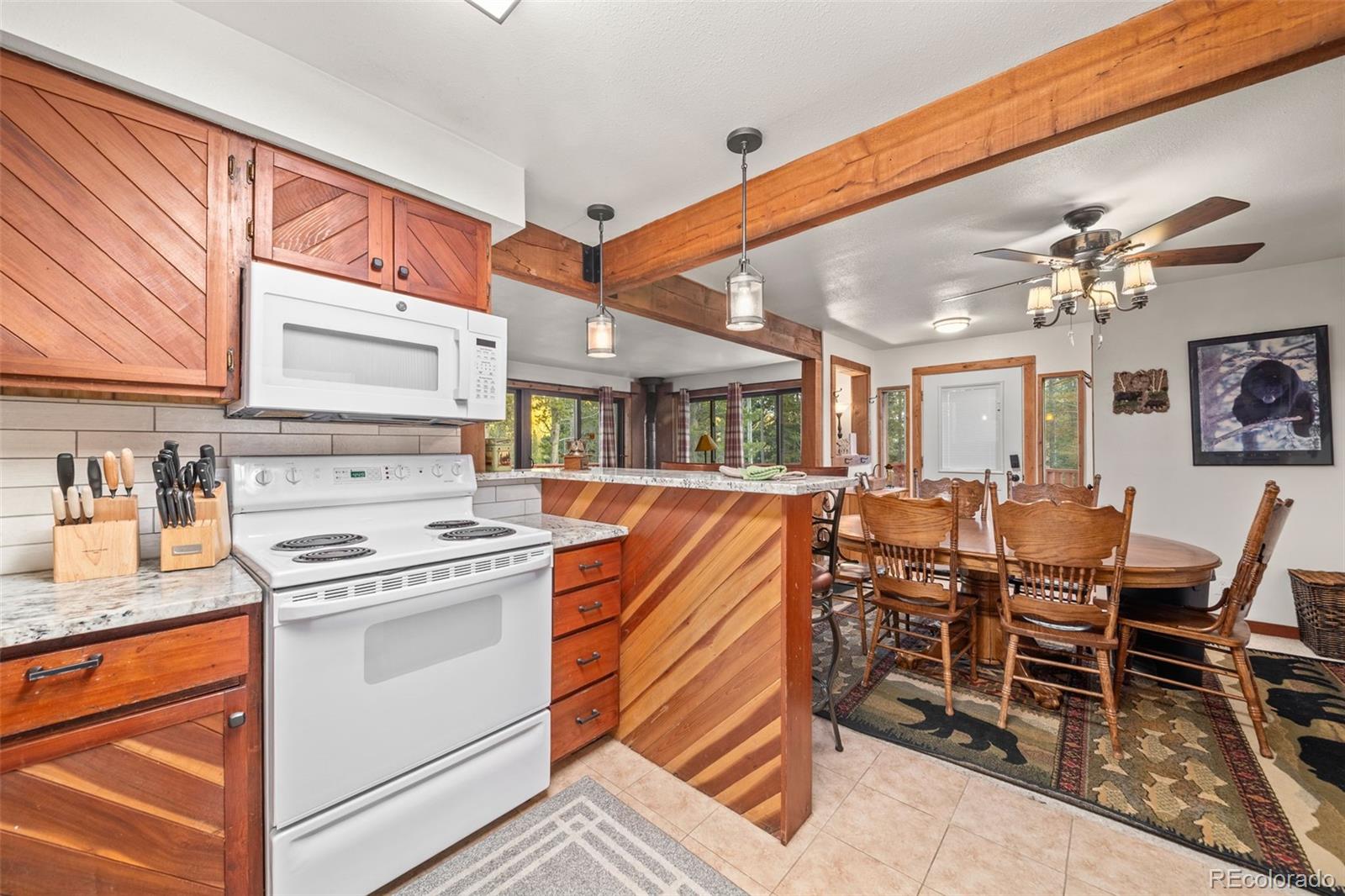 838 Silver Creek Road Idaho Springs, CO 80452 - Photo 5 of 29 a open kitchen with stainless steel appliances granite countertop a stove top oven a dining table and chairs with wooden floor