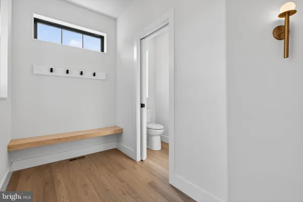 a kitchen with stainless steel appliances kitchen island a refrigerator a stove and white cabinets with wooden floor