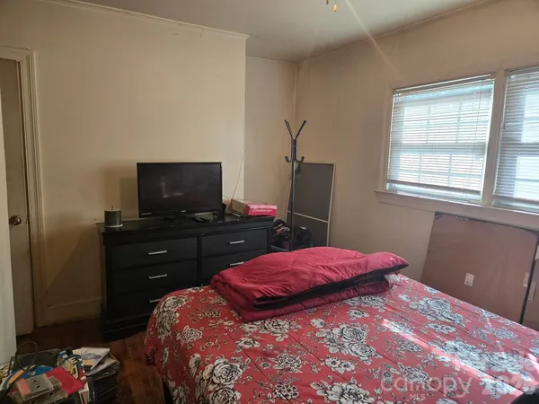 a bedroom with a bed and a flat tv screen on the dresser