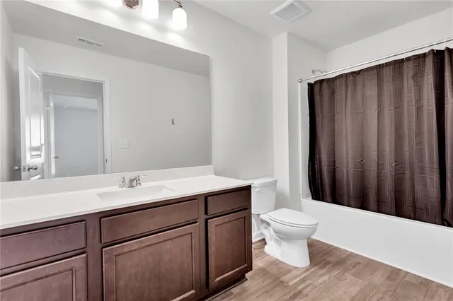 a bathroom with a sink a toilet a shower and a large mirror