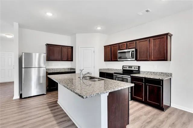 a kitchen with kitchen island granite countertop stainless steel appliances and wooden cabinets