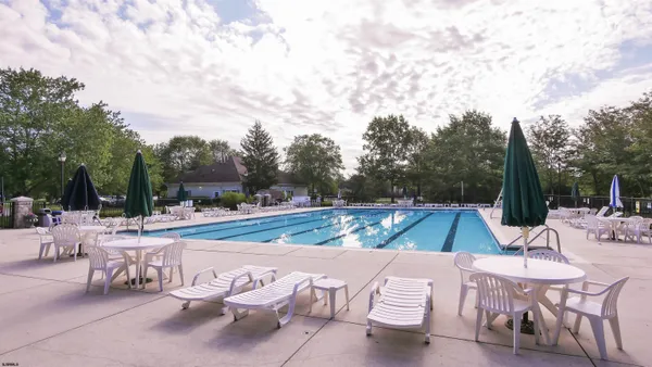 a view of a swimming pool with chairs and a small yard