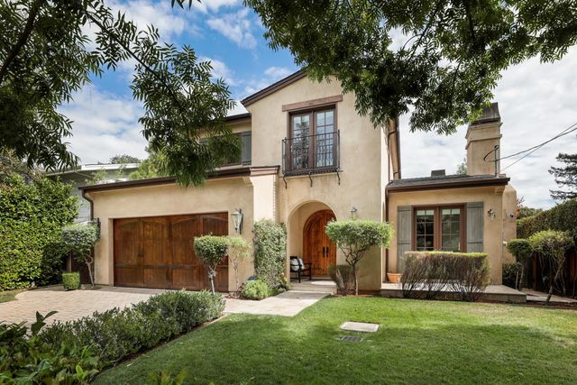 a view of a yard in front of a house with plants and large tree