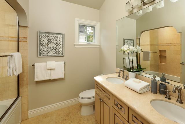 a bathroom with a granite countertop toilet sink and mirror