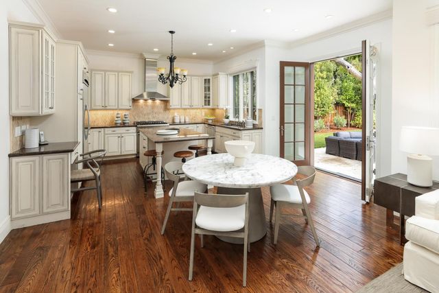 a kitchen with stainless steel appliances granite countertop wooden floor dining table and chairs