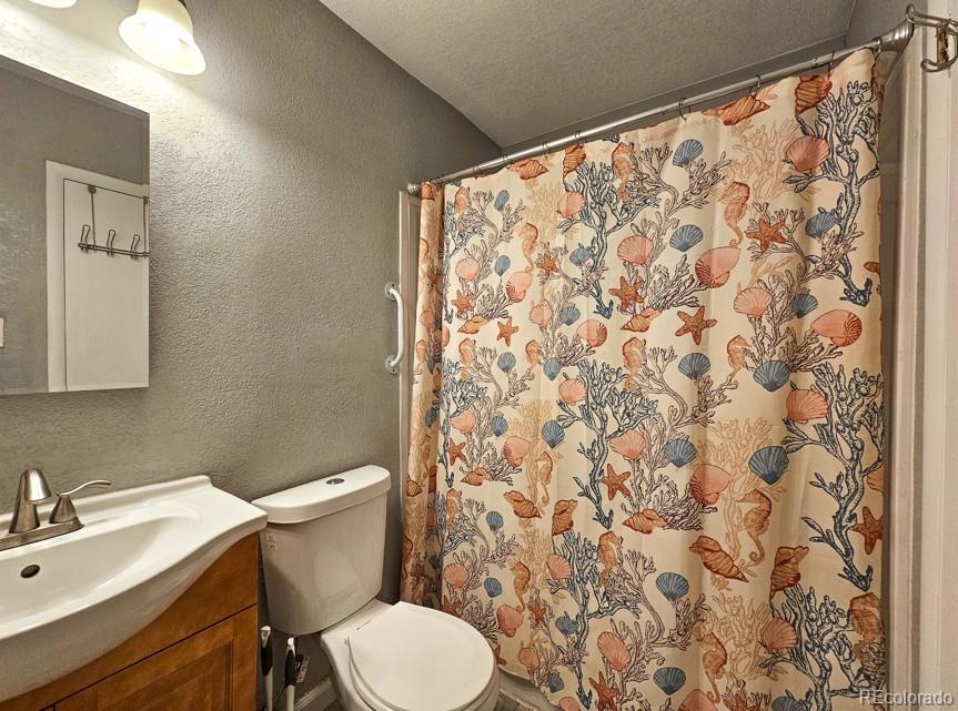 5542 Scranton Street Denver, CO 80239 - Photo 22 of 36 a white toilet sitting next to a shower curtain