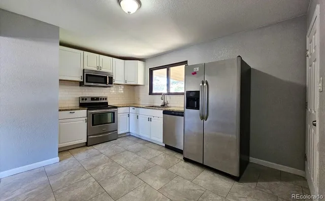 a kitchen with granite countertop a refrigerator stove and microwave