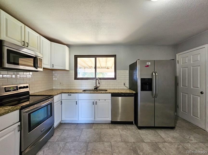 5542 Scranton Street Denver, CO 80239 - Photo 6 of 36 a kitchen with stainless steel appliances granite countertop a stove a sink and a microwave