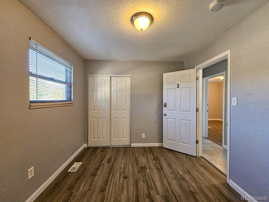 5542 Scranton Street Denver, CO 80239 - Photo 10 of 36 an empty room with wooden floor and windows