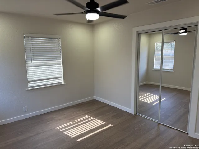 an empty room with wooden floor cabinet and windows