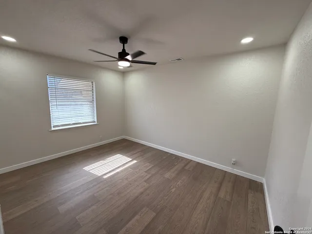 an empty room with a window and ceiling fan