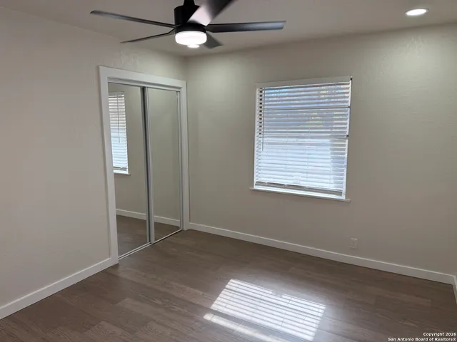 an empty room with wooden floor fan and windows