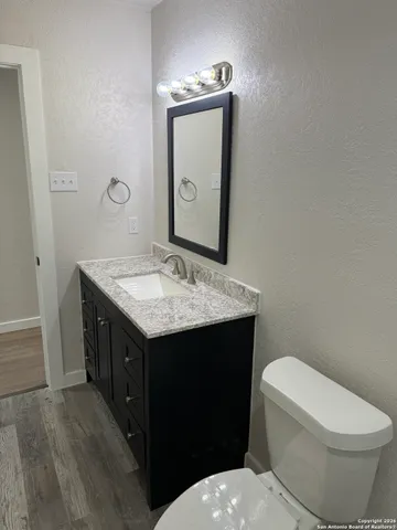 a bathroom with a granite countertop toilet sink and mirror