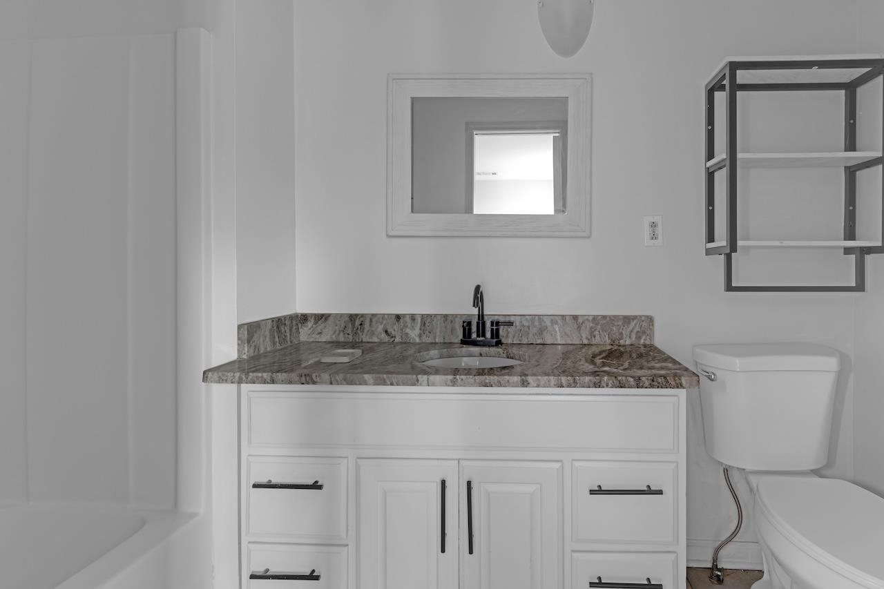 4251 Riviera Drive Memphis, TN 38108 - Photo 12 of 16 a bathroom with a granite countertop sink a toilet and mirror